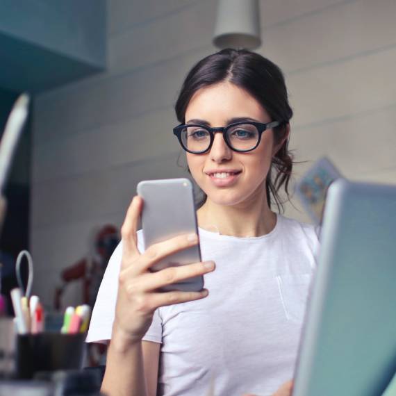 young woman wearing glasses looking at her smartphone