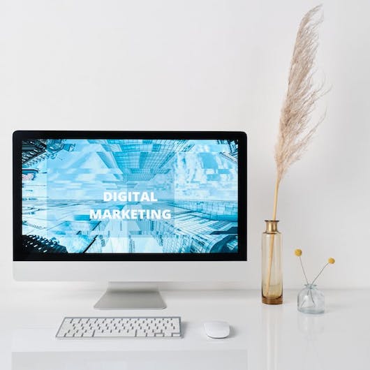 Ein Schreibtsich, dekoriert mit einer Pflanze, ein Computer mit einem blauen Bildschirm, auf dem steht Digital Marketing. effektive Landing Page erstellen.