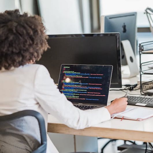 Frau sitz am Schreibtisch und betrachtet den Bildschirm ihres Laptops