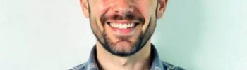 Ein Mann mit Bart und blaues Hemd der lächelt