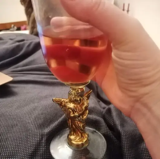 a hand holding a glass of rose wine