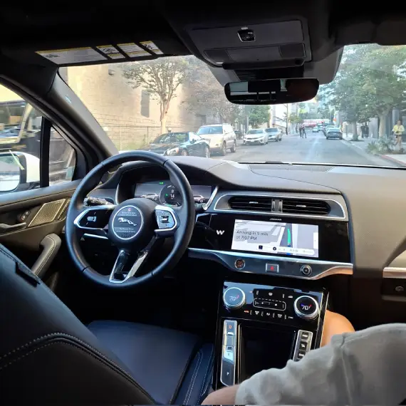 inside a Waymo car driving down the street
